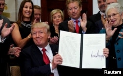 President Donald Trump smiles after signing an executive order to make it easier for Americans to buy bare-bones health insurance plans and circumvent Obamacare rules, at the White House in Washington, Oct. 12, 2017.