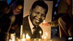 Warga menyalakan lilin di depan foto mantan presiden Afrika Selatan Nelson Mandela di Trocadero Square, Paris. 