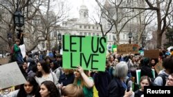 Students hold banners and posters during a demonstration against climate change in New York, March 15, 2019. 