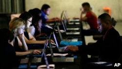 FILE - In this May 19, 2017, photo, job seekers work on their resumes during the Opportunity Fair and Forum employment event in Dallas. 