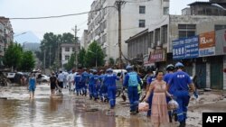 Rescue workers and local residents are seen walking through a flooded street following two days of relentless rain and storms, in Gongyi, near Zhengzhou, in central China’s Henan province, July 22, 2021.