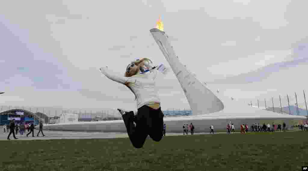 Evgenii Itbaev leaps as a friend takes her picture near the Olympic Cauldron at the 2014 Winter Olympics, Feb. 14, 2014.