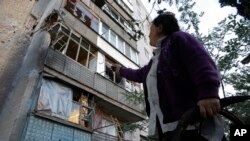 A woman points to a damaged building after shelling in the city of Slovyansk, Donetsk region, eastern Ukraine, June 29, 2014.