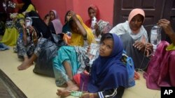 Ethnic Rohingya women and children sit on the floor upon arrival at a temporary shelter after their boat landed in Pidie, Aceh province, Indonesia, Dec. 26, 2022.