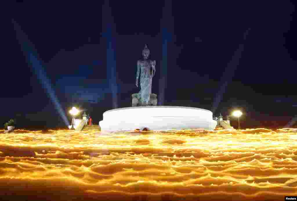 Umat Budha membawa lilin-lilin, membentuk lautan api, mengelilingi sebuah patung Budha besar pada hari Raya Waisak, untuk memperangati kelahiran, pencerahan dan wafatnya Sang Budha di kuil di Provinsi Nakhon Pathom di pinggiran kota Bangkok. 