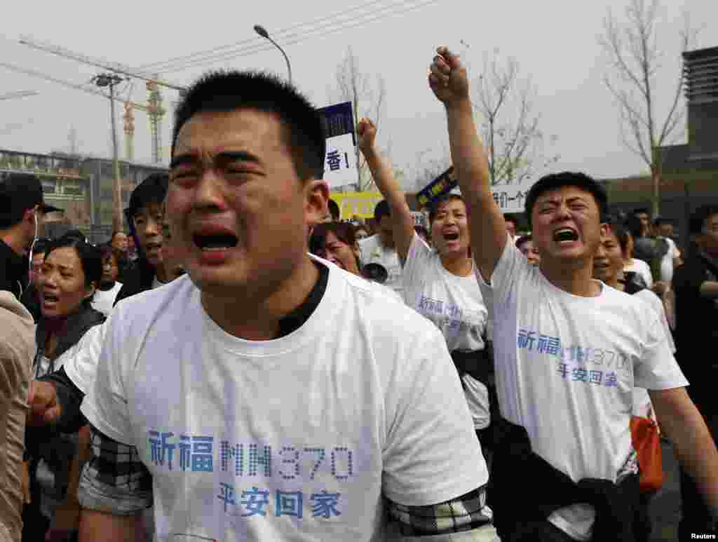 Keluarga penumpang penerbangan MH370 menangis sambil meneriakkan slogan dalam demo di depan kedutaan Malaysia di Beijing, 25 Maret 2014.