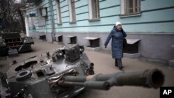 Seorang perempuan berjalan di dekat tank Rusia yang hancur dipajang di sebuah jalan di Kyiv tengah, Ukraina, Rabu, 25 Januari 2023. (Foto: AP/Daniel Cole)
