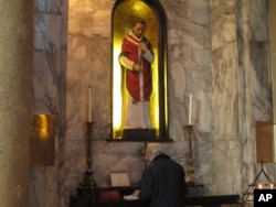 FILE - A worshipper stands at the altar of St. Valentine in the Carmelite Church in Whitefriar Street, Dublin, Jan. 2, 2014.