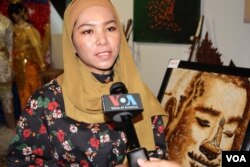 អ្នក​នាង​ Aisha ស្ថាបនិក​ក្រុមហ៊ុន​គំនូរ​គ្រាប់​អង្ករ នៅ​ក្នុង​បទសម្ភាសន៍​មួយ​នៅ​ក្នុង​សារមន្ទីរ​មរតក​ខ្មែរ​ក្នុង​ទី​ក្រុង​ Saint Paul រដ្ឋ​មីនីសូតា​កាលពី​ថ្ងៃ​ទី​២៧​ខែ​ឧសភា​ឆ្នាំ២០១៩។ (សាយ មុន្នី/VOA)