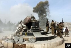 FILE - Turkey-backed Free Syrian Army soldiers celebrate around a statue of Kawa, a mythology figure in Kurdish culture, after destroying it in the city center of Afrin, northwestern Syria, March 18, 2018.