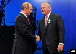 FILE - Russian President Vladimir Putin presents ExxonMobil CEO Rex Tillerson with a Russian medal, June 21, 2012.