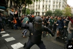 Spanish riot police swings a club against would-be voters near a school assigned to be a polling station by the Catalan government in Barcelona, Oct. 1, 2017.