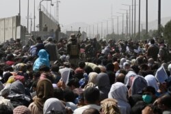 Afghans gather on a roadside near the military part of the airport in Kabul, Aug. 20, 2021, hoping to flee from the country after the Taliban's military takeover of Afghanistan.