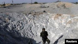 A Palestinian militant inspects a crater caused by what police said was an Israeli air strike in Khan Younis in the southern Gaza Strip, June 29, 2014. 