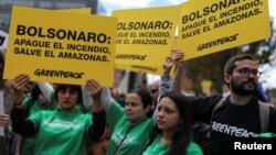 FILE - Demonstrators hold placards that read "Bolsonaro: extinguish the fire, save the Amazon" during a protest outside the Brazilian embassy due to the wildfires in the Amazon rainforest, in Bogota, Colombia August 23, 2019. (REUTERS/Luisa Gonzalez)