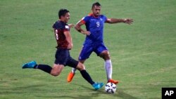 FILE - India's Robin Singh, right, and Guam's Mason Douglas in action as it rains during their 2018 FIFA World Cup qualifying soccer match in Bangalore, India, Nov. 12, 2015.