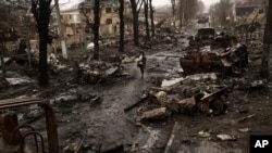 Žena hoda pored uništenih ruskih tenkova u Buči u Ukrajini, 3. aprila 2022. (Foto: AP / Rodrigo Abd)