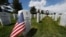 A flag stands next to the gravestone for a U.S. World War II veteran, at Fort Logan National Cemetery, in Sheridan, Colorado, May 23, 2020. 