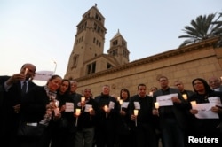 FILE - Egyptians hold candles in front of the Coptic Christian Cathedral in al-Beheira in tribute to the victims of a bomb attack inside a Coptic cathedral in Cairo, Dec. 17, 2016.