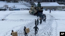 In this photo provided by Japanese Ministry of Defense, members of Japan Self-Defense Forces carry relief goods in the earthquake-hit city Wajima, Ishikawa prefecture, Japan, Jan. 8, 2024.