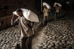 FILE - Workers carry sacks of wheat for food distribution to people who fled the violence in Ethiopia's Tigray region, organized by the local NGO Relief Society of Tigray, in Mekelle, the capital of Tigray region, June 22, 2021.