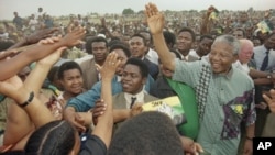 African National Congress President Nelson Mandela, right, waves to the gathered crowd at Jouberton Township stadium as people reach out to touch him during a campaign rally on Jan. 30, 1994.