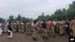 Ethiopian soldiers block the street as people march during an annual religious festival in Bishoftu, a town southeast of Ethiopia's capital, Addis Ababa, Sunday, Oct. 2, 2016.