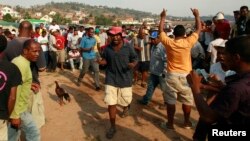 In this 2013 file photo, men cheer after winning a bet during the traditional Malagasy cockfighting (combat des coqs) contest in Ambohimangakely near Madagascar's capital Antananarivo.