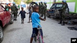 FILE - Children play in the street while United Nations peacekeepers from Brazil patrol in the Cite Soleil slum, in Port-au-Prince, Haiti, Feb. 22, 2017. 