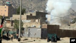 Smoke rises from a house where suspected attackers were hiding while policemen arrests two suspects, left, in Kabul, Afghanistan, Aug. 21, 2018.