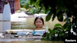Seorang perempuan mengarungi jalanan di kota kuno Hoi An yang terendam banjir , setelah topan Damrey melanda Vietnam, 6 November 2017.