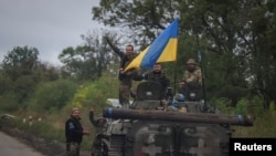 在刚从俄军手中收复的乌克兰东北部哈尔科夫州伊久姆镇，乌克兰军人站在竖着乌克兰国旗的BMP-1步兵战车上。（2022年9月14日）