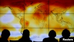 FILE - Participants are seen in silhouette as they look at a screen showing a world map with climate anomalies during the World Climate Change Conference 2015 (COP21) at Le Bourget, near Paris, France, Dec. 8, 2015. 