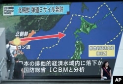 FILE - People walk past a public TV screen broadcasting news of North Korea's launch of its second intercontinental ballistic missile, in Tokyo, July 29, 2017.