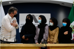 The Mexican Secretary of Foreign Affairs Marcelo Ebrard (L) welcomes four Afghan women, members of the Afghanistan Robotic team, during their arrival to Mexico after asking for refuge, at the Airport in Mexico City, on August 24, 2021.