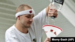 A man pours from a bottle into a drinking device before a football game between Wisconsin University and Western Illinois University.