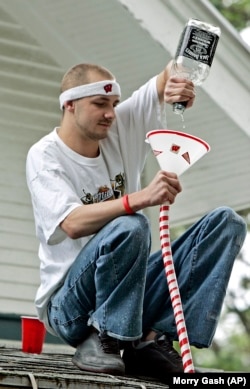 A man pours beer from a Jack Daniels bottle into a drinking device before a football game between Wisconsin University and Western Illinois University.