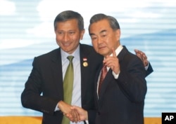 FILE - Singapore's Foreign Minister Vivian Balakrishnan, left, shakes hands with Chinese Foreign Minister Wang Yi, right before they pose for a photo during the ASEAN – China Foreign Ministers' Meeting in Vientiane, Laos, July 25, 2016.