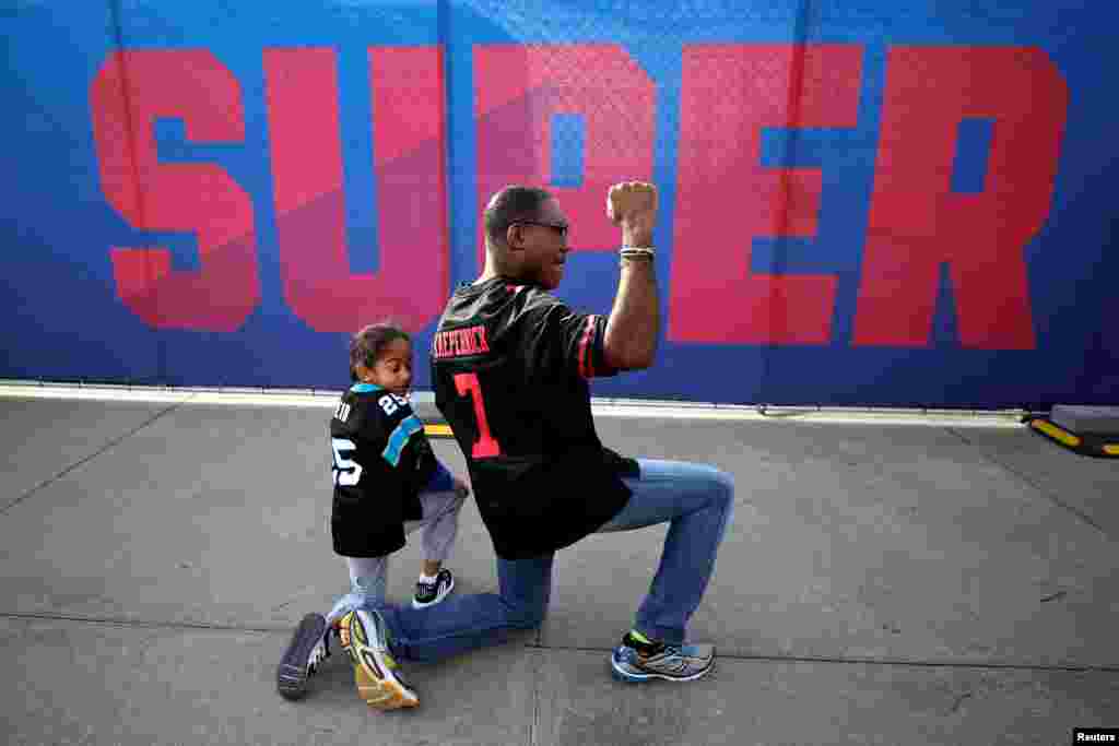 Anar Kahn from Atlanta, kneels with his son while wearing a Colin Kaepernick football jersey outside Mercedes Benz Stadium ahead of Super Bowl LIII in Atlanta, Georgia, Feb. 2, 2019.