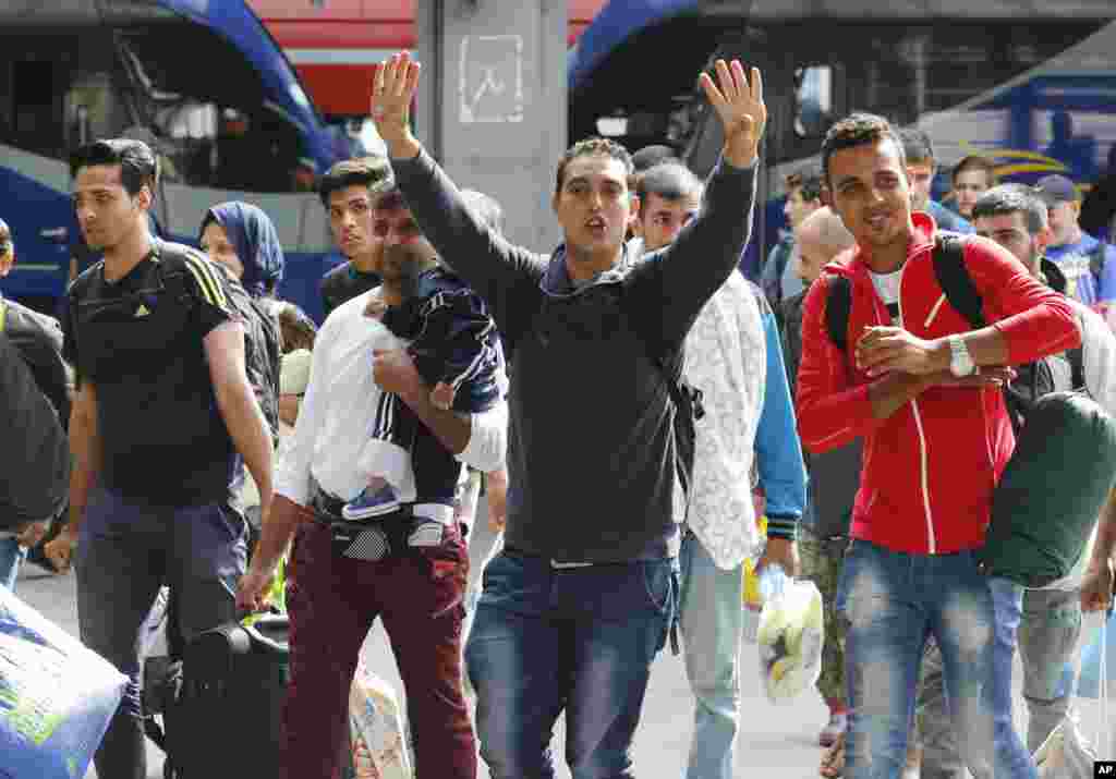 Refugees wave as they arrive at the main train station in Munich, Germany, Sept. 5, 2015. 