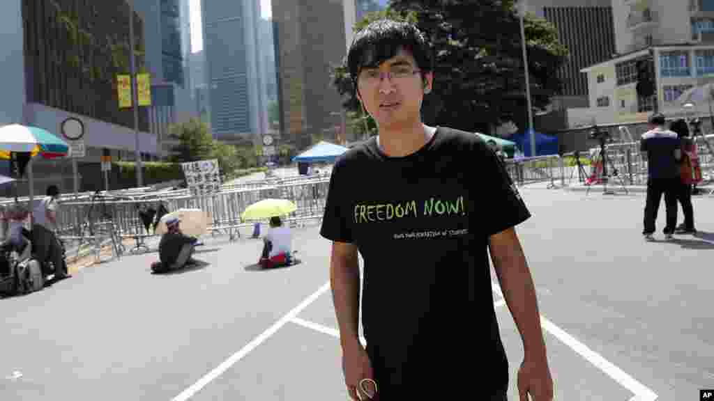 Pro-democracy student leader Alex Chow walks by Hong Kong's Chief Executive Leung Chun-ying's office where a few student protesters are sitting and staging their protest in Hong Kong, Oct. 6, 2014.