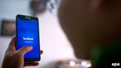 FILE - A man uses the social networking site Facebook on his phone in a cafe in Hanoi, Vietnam, 28 November 2013. (EPA/LUONG THAI LINH)