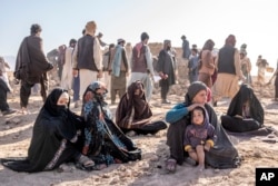 زنان و کودکان افغانستانی در مقابل خانه‌های خود که در اثر زلزله در حوزه زنده‌جان در ولایت هرات، ویران شده، نشسته اند - ۱۹ مهر ۱۴۰۲