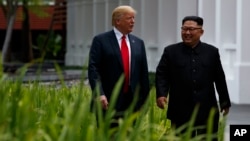 President Donald Trump walks with North Korean leader Kim Jong Un on Sentosa Island, Tuesday, June 12, 2018, in Singapore.