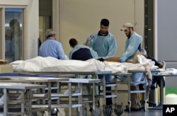 Medical personnel examine a body at the Orlando Medical Examiner's Office, June 12, 2016, in Orlando, Florida.
