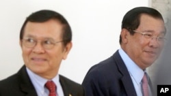 Cambodia's Prime Minister Hun Sen, right, walks with opposition Cambodia Rescue Party Deputy President Kem Sokha, left, during a break at National Assembly in Phnom Penh, Cambodia, Wednesday, Dec. 7, 2016.
