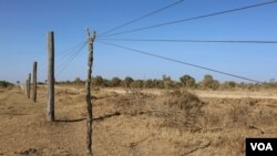 Wires of a fence are propped up in order for herders’ livestock to pass through into Mugie Conservancy, Laikipia, Kenya, March 17, 2017. (J. Craig/VOA)
