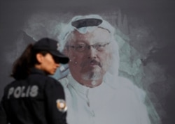 A Turkish police officer walks past a picture of slain Saudi journalist Jamal Khashoggi prior to a ceremony, near the Saudi Arabia consulate in Istanbul, marking the one-year anniversary of his death, Wednesday, Oct. 2, 2019.