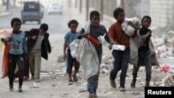 Anak-anak mengumpulkan botol-botol plastik di sebuah jalan di Sanaa, Yaman, 21 November 2019. 