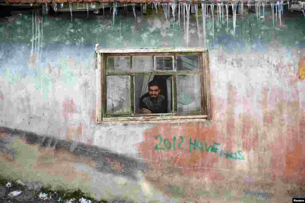 Seorang laki-laki memandang ke jalan melalui jendela sementara serpihan-serpihan es menggantung di atap rumahnya di distrik Hacibayram di Ankara, Turki.&nbsp; Badai minggu ini mengakibatkan badai salju, hujan dan suhu yang rendah di Timur Tengah. &nbsp;